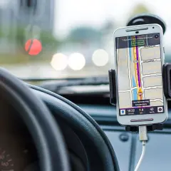 Telefon z nawigacją GPS zamontowany w samochodzie, obok kierownicy.