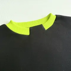 Czarny sweter z neonowożółtym ściągaczem przy dekolcie. Pokazuje, jak przerobić okrągły dekolt na bardziej oryginalny.