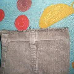 Brązowe spodnie z surowym wykończeniem u dołu, idealne, by dowiedzieć się, jak przedłużyć spodnie. Tło w kropki.