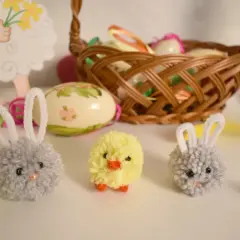 Wielkanocne ozdoby: pompony zajączki i kurczaczek, koszyk z pisankami.