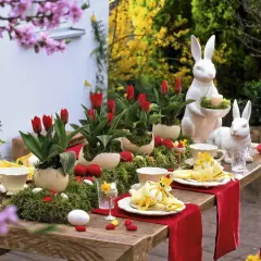 Stół wielkanocny z tulipanami, jajkami i ceramicznymi królikami.