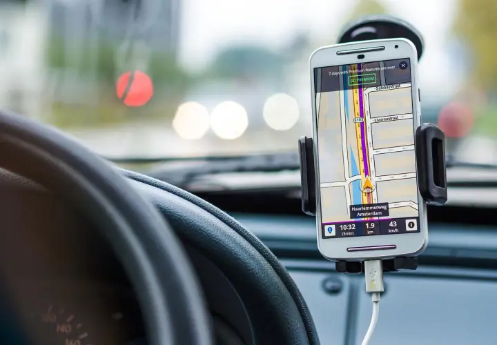 Telefon z nawigacją GPS zamontowany w samochodzie, obok kierownicy.