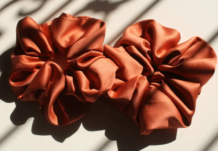 Dwa satynowe scrunchie w kolorze miedzianym, idealne do nauki, jak uszyć scrunchie.