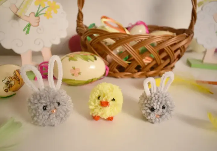 Wielkanocne ozdoby: pompony zajączki i kurczaczek, koszyk z pisankami.