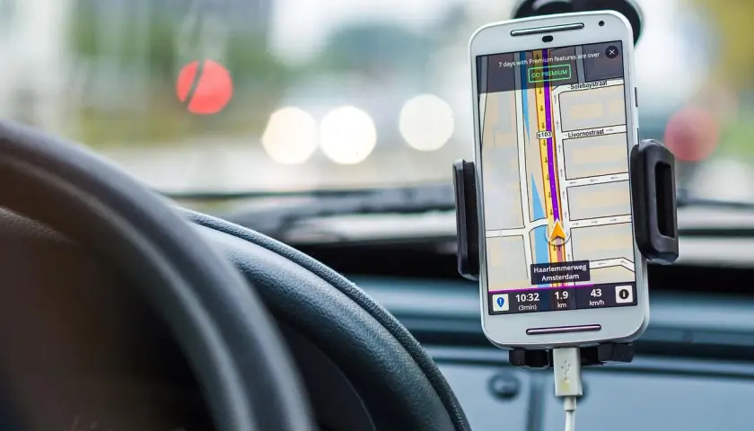 Telefon z nawigacją GPS zamontowany w samochodzie, obok kierownicy.