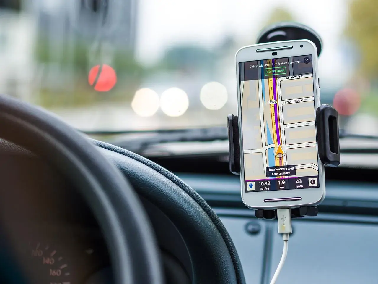 Telefon z nawigacją GPS zamontowany w samochodzie, obok kierownicy.