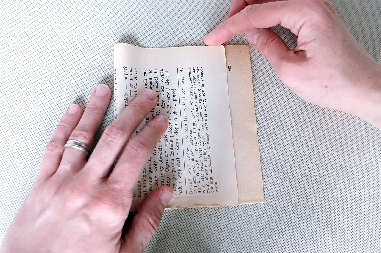 Składanie kartki z książki, by stworzyć torebkę na prezent. Prosty sposób, jak zrobić torebkę na prezent z papieru.