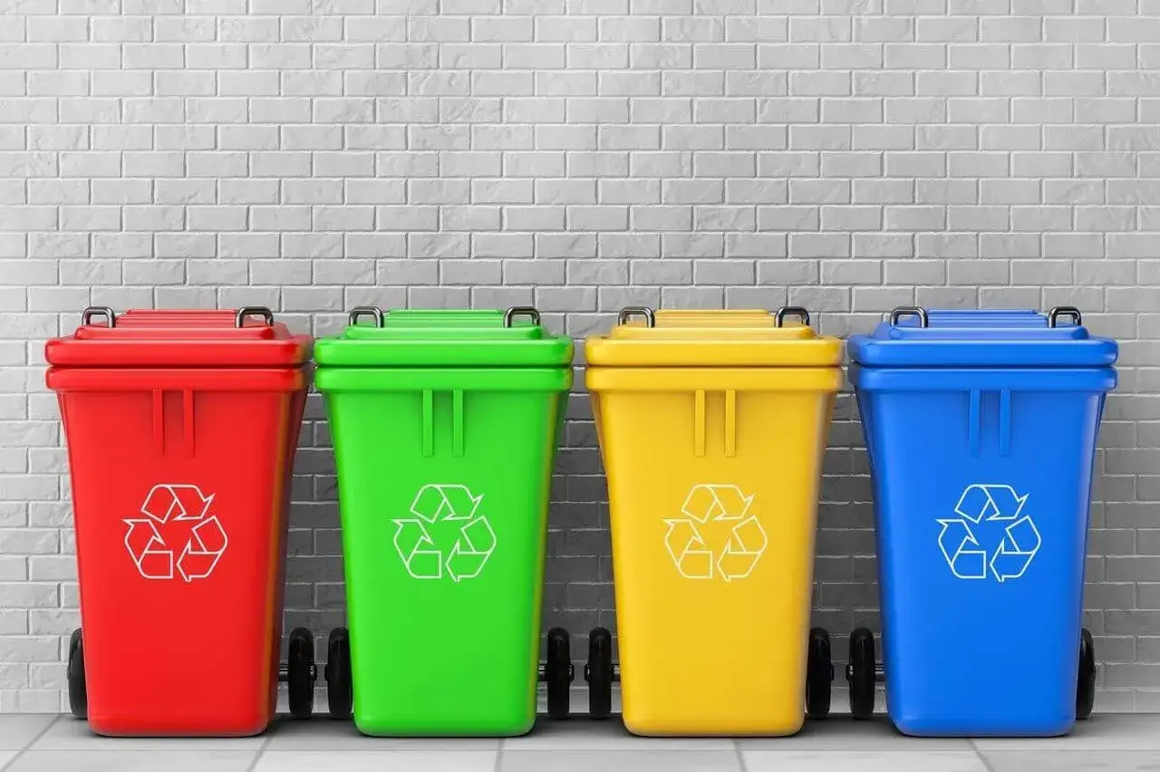 Cztery kolorowe kosze na śmieci z symbolem recyklingu. Zastanawiasz się, gdzie wyrzucić opakowanie po galaretce? Sprawdź oznaczenia na koszach!