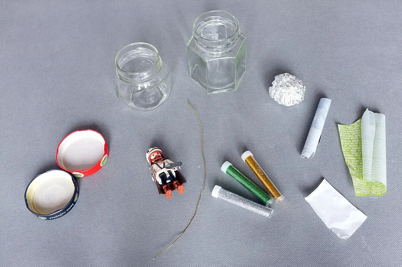 Potrzebne do tego, jak zrobić kulę śnieżną: słoiki, figurka, brokat, folia aluminiowa, sznurek i papier.